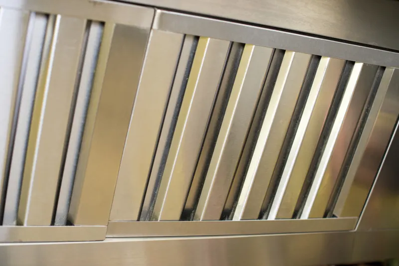 Stainless steel baffle filters and cooking equipment in a commercial kitchen during a deep clean