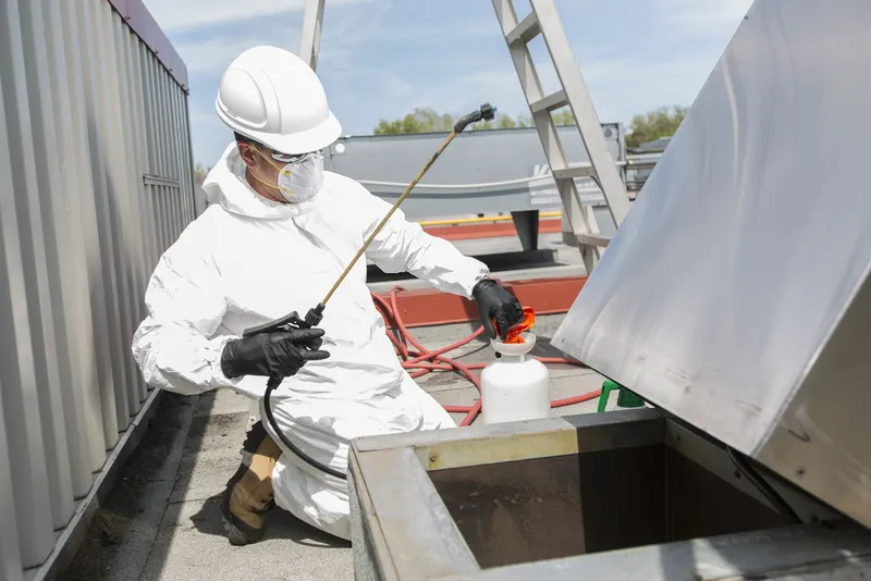 Rooftop upblast kitchen exhaust fan on a raised curb with its housing tilted open on a hinge